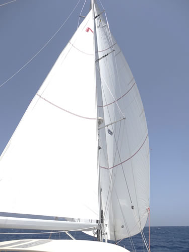 note the difference between the apparent wind off the mainsail displayed by the Greek courtesy flag compared to the true wind illustrated by the burgees at the top spreader’